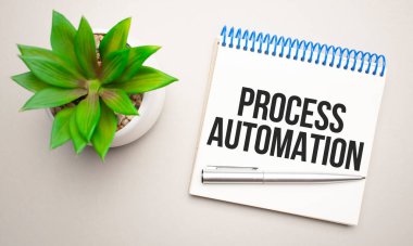 İşlem Otomatiği, bir not panosu, hesap makinesi, yeşil bitki, gözlük ve sarı ve beton bir arka plan üzerinde bir kalem yakınındaki beyaz bir not defterine yazılır..