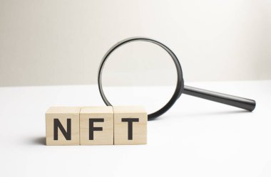 İş konsepti. Belgelerde NFT yazılı küpleri gösteren bir büyüteç var.