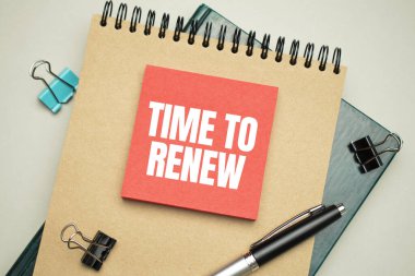 Masaüstünde raporlar, not defterleri, bir hesap makinesi, bir nakit para ve yenilenmek için metin zamanı yazılı sarı bir çıkartma var. İş konsepti