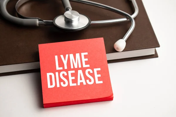 stock image Medicine and health concept. On a white table lies a stethoscope, pills and a notebook with the inscription - Lyme disease