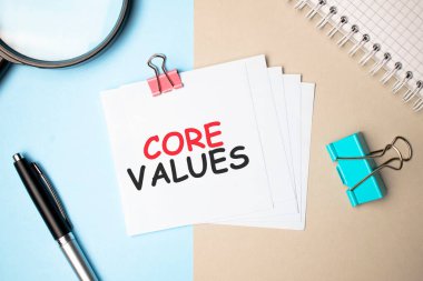 Hafif arka plan büyüteci, kalem ve üzerinde Ana Değerler yazan bir defter. İş konsepti