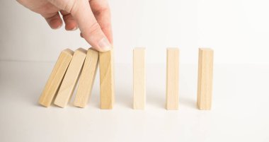 İşadamı sürekli risk almak, sürekli hasar azaltmak, iş dominosu başarısızlıklarını durdurmak için domino taşının üzerine düşen elleri durdurur..