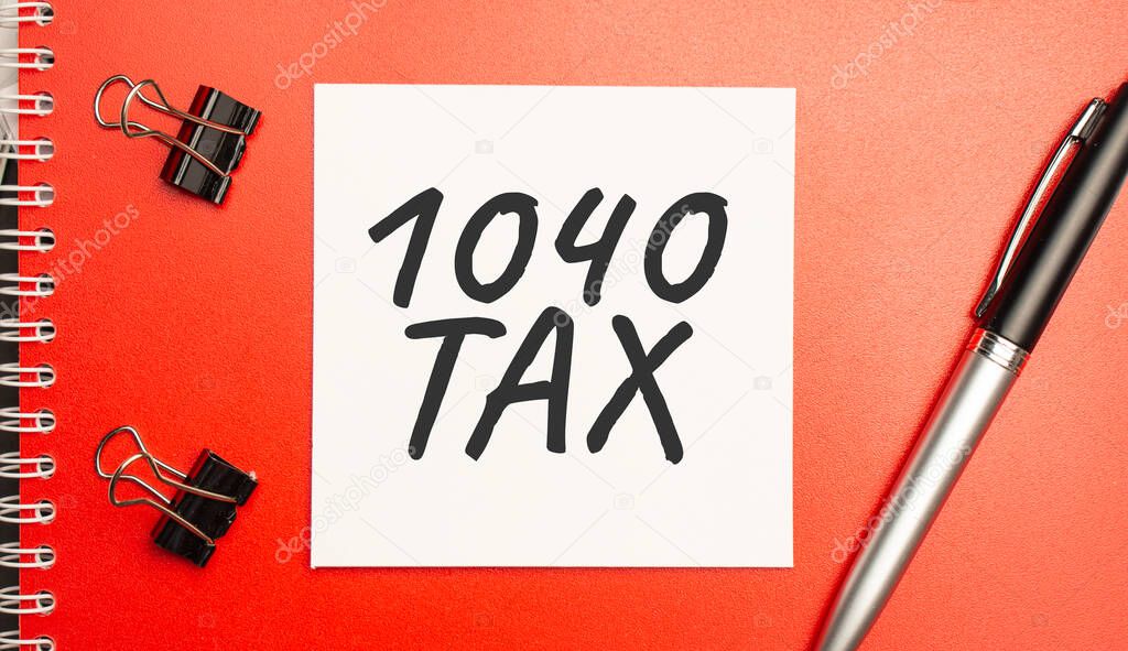 1040 tax sign on sheet of paper on the red notepad with pen