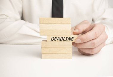 Son teslim tarihi iş süreci sembolü. Tahta bloklar beyaz arka plandaki basamaklar gibi istifleniyor, kopyala uzayı. İşadamı eli..