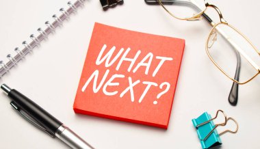 Masaüstünde raporlar, not defterleri, bir hesap makinesi, bir nakit para ve içinde What NEXT yazan kırmızı bir etiket var. İş konsepti