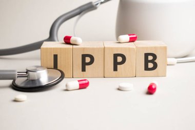 Ippb kelimesi sarı arkaplandaki ahşap küplerden ve haplardan oluşur. tıbbi tedavi, önleme ve yan etkiler kavramı.