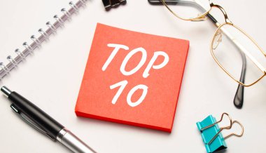 Masaüstünde raporlar, not defterleri, hesap makinesi, nakit para ve en iyi 10 metni içeren kırmızı bir çıkartma var. İş konsepti