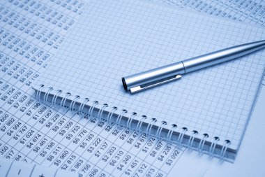 Finansal belgelerde sayılar sütunları olan siyah bir hesap makinesi ve vizyon için gözlük var. İş ve mali konsept.