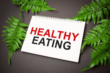 Koyu arkaplanda bitki olan kağıdın üzerinde sağlıklı beslenme metni