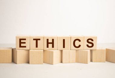 Ahşap blokta ETHICS metni ve ahşap arka planda ofis araçları