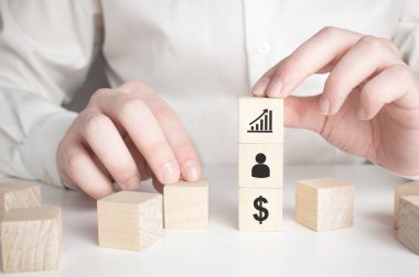 İş büyümesinin başarısı için dolar sembolü simgesine işaret eden oklarla el ele tutuşan tahta küp