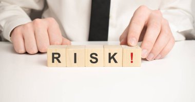 Açık mavi ahşap zemin üzerinde RISK yazısıyla tahta küpleri.