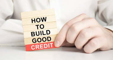 İyi bir kredi sembolü oluştur. Sözcüklerle ahşap bloklar nasıl iyi kredi oluşturulur. Ampul simgesi. Kalemle çalışan bir iş adamı. Güzel mavi arkaplan, kopyalama alanı. İş ve iyi kredi konsepti oluşturmak.