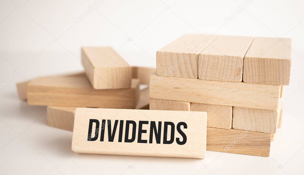 DIVIDEND word text from wooden cube block letters on braided rattan mats background.