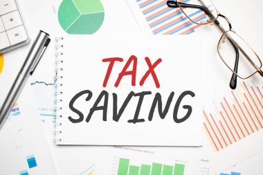 Masadaki ve iş dünyasındaki raporların arkaplanındaki mavi kartta vergi tasarrufu.