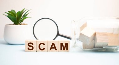 Kahverengi arka planda tahta bloklarla yazılmış SCAM kelimesi, konsept