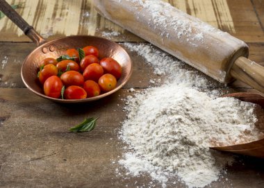 Küçük bakır kapta kiraz domatesleri, merdane, fesleğen yaprağı ve un..