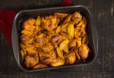 Patatesli fırında tavuk ve siyah kabın içinde sade ahşap. en üstteki görünüm