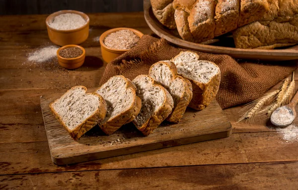 用芝麻籽 胚芽胶 制成的切片面包 放在带有其他面包和配料的乡村木桌上 — 图库照片
