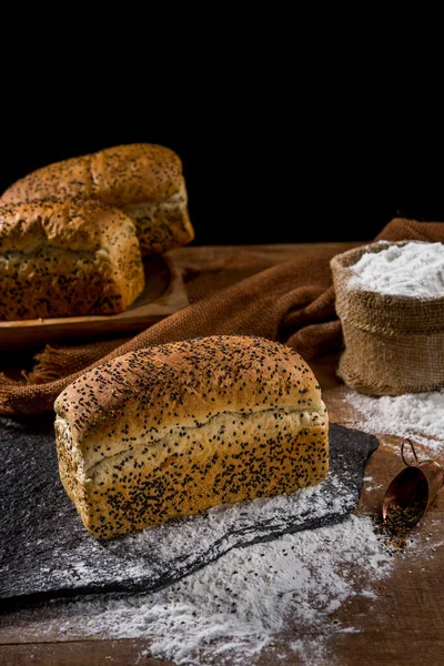 面包面包 用芝麻籽 胚芽胶 放在乡村木桌上 其他面包和配料为背景 — 图库照片
