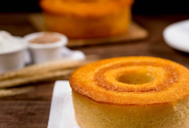 Tahtadaki buğday unu keki ve arka plandaki diğer pastalarla birlikte buğday dalı..