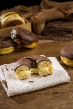 Kremalı çöreğin yarısı çikolatalı kremayla kaplı diğer çöreklerle ahşap üstüne krema ve...