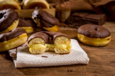 Kremalı çöreğin yarısı çikolatalı kremayla kaplı diğer çöreklerle ahşap üstüne krema ve...