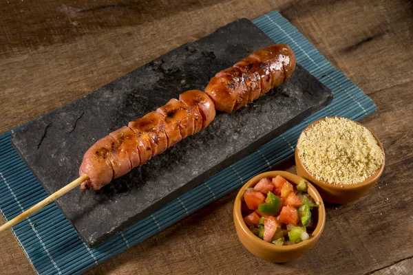 sausage barbecue on a stick on wooden background ( churrasquinho de linguica).