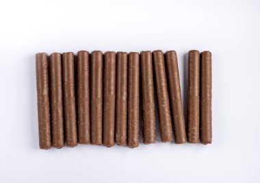 Çikolata kaplı gofret rulosu yan yana dizilmiş beyaz arka planda, üst görünümde izole edilmiş.