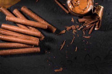 Çikolata kaplı gofret siyah desenli arka plan üzerinde rulo kırsal ayar, üst görünüm, kopyalama alanı