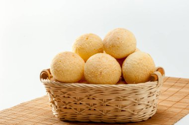 Peynirli ekmek, beyaz arka planda izole edilmiş bambu paspasın üzerinde geleneksel Brezilya yemeği (pao de queijo)