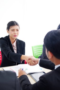 Gülümseyen başarılı Asyalı iş kadını, ofisteki toplantı odasında proje için eşiyle tokalaşıyor. İş ve pazarlama kavramı.