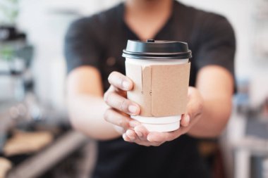 Asyalı genç baristanın eli kapalı bir şekilde kafede bir fincan sıcak kahve tutuyor. Kafe ve kafe işletme konsepti başlat.. 
