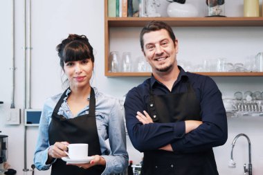 Gülümseyen Kafkasyalı genç barista çifti aşk ya da ortaklık elbisesi giyiyor ve kahve dükkanında çalıştığı için mutlu. Küçük kafe işletme sahibi konsepti için başla. 