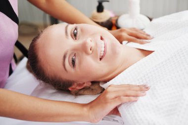 Profesyonel Asyalı Masaj Terapisti kadın, Tayland 'daki alternatif tıp tedavi merkezindeki yatakta dinleniyor ve gülümsüyor..