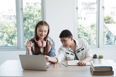 Gülümseyen beyaz öğrenciler veya öğrenciler kulaklıkla çevrimiçi müzik öğreniyor. Onlar sınıfta birlikte dizüstü bilgisayarla bilgi araştırıyorlar. Eğitim ve Teknoloji Konsepti.