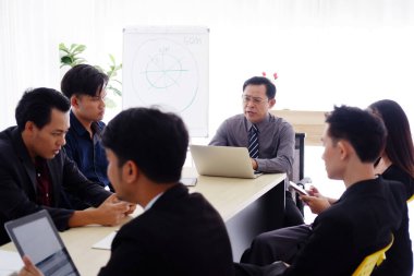 Asya 'nın kıdemli başarılı yöneticisi, iş adamlarıyla toplantı ve beyin fırtınası yapıyor ve pazarlama ve borsa işleri ile ilgili takım çalışmalarını ofisdeki toplantı odasında yapıyor.