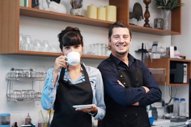 Gülümseyen Kafkasyalı genç barista çifti aşk ya da ortaklık elbisesi giyiyor ve kahve dükkanında çalıştığı için mutlu. Küçük kafe işletme sahibi konsepti için başla. 