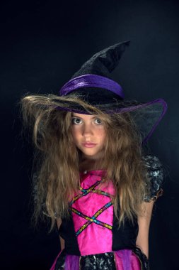 Cadı gibi giyinmiş bir kız ve Cadılar Bayramı için geniş kenarlı bir şapka..