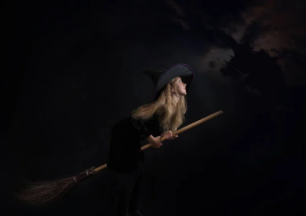 Egy Kislány Sötét Háttérben Boszorkányjelmezben Egy Széles Karimájú Kalap Repül — Stock Fotó