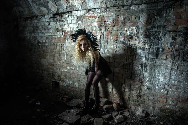 万圣节夜晚 一个穿着鲜艳服装 头戴羽毛的女巫的形象出现在地牢的一面古老的砖墙后面 — 图库照片