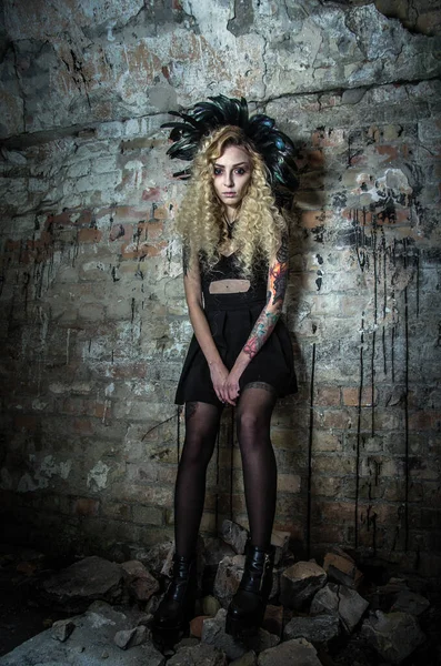 ダンジョンの古いレンガの壁の背景にハロウィーンの夜に羽を持つ明るい衣装で魔女のイメージの女性 — ストック写真
