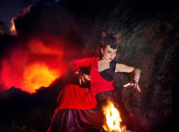 ハロウィーンの夜の魔女をイメージした女性が炎の近くで — ストック写真