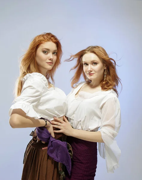 Photoshoot with two red-haired girls - sisters in the studio on a blue background.