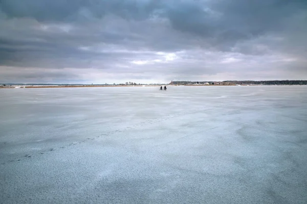 Two cyclists ride on the ice of a frozen lake. — Stock Photo, Image