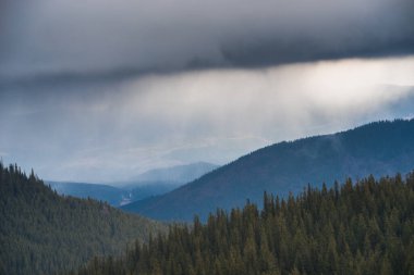 Karanlık bir kış gökyüzünün altında karlı kış dağları.