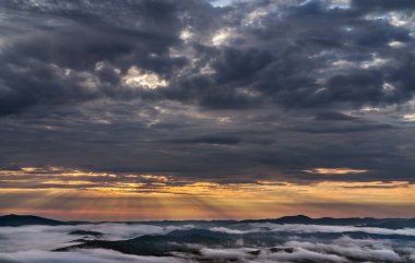 Güneşin doğuşu ve bulutlu gökyüzü dağların üzerinde. Dağların zirvesinde, siste. Bulut düzeni.
