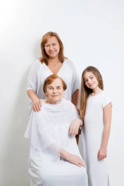 Soft group portrait of women of the same family of different generations in light clothes on a white background. — Stock Photo, Image