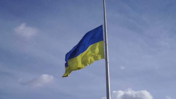 Žlutomodrá národní vlajka Ukrajiny vlaje proti zamračené modré obloze. — Stock video
