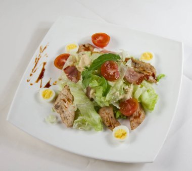 Kızarmış tavuk eti ve beyaz tabakta taze salata..